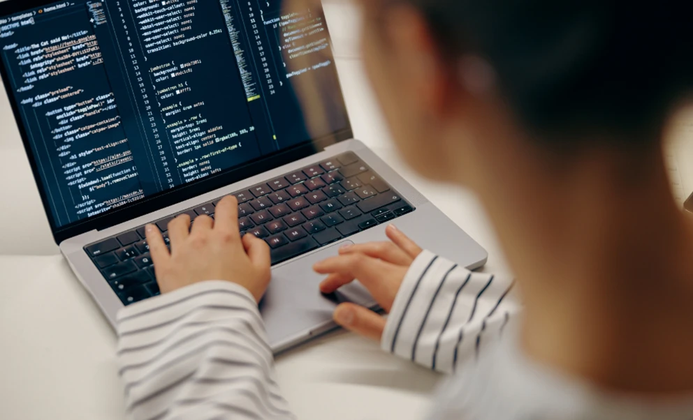 Programadora escribiendo código en un ordenador portátil.